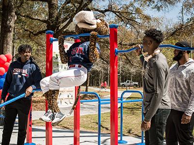 Southpaw doing a pull up the Jag Fitness Trail as students look on.